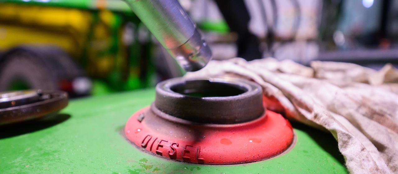 Ein Landwirt betankt ein Fahrzeig in seiner Fahrzeughalle mit Diesel.
