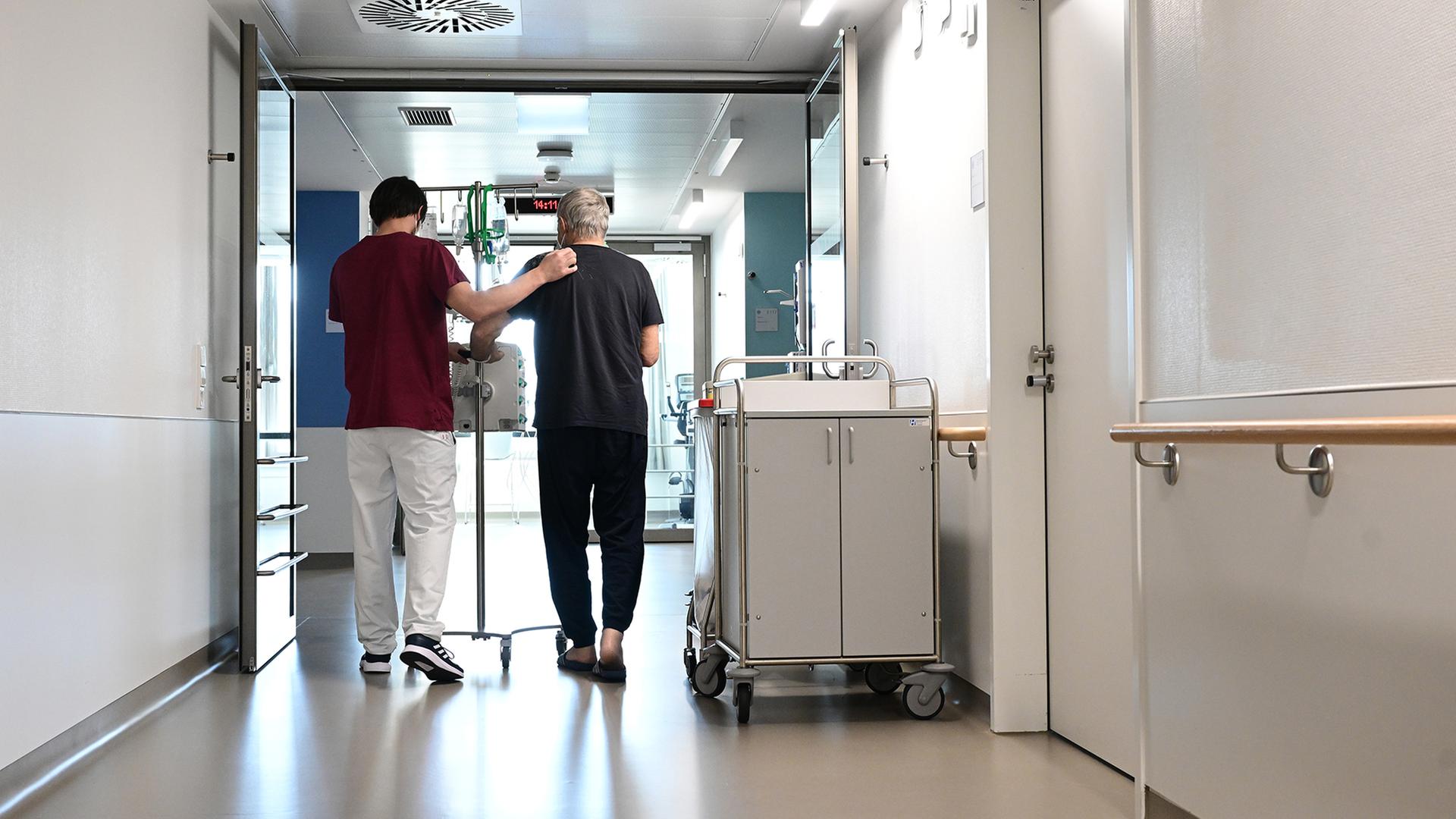 Ein Pfleger geht mit einem Patienten über einen Krankenhausflur.  | dpa