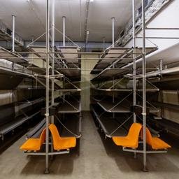 Blick in einen Bunkerraum in Nürnberg mit Etagenbetten und Sitzen.