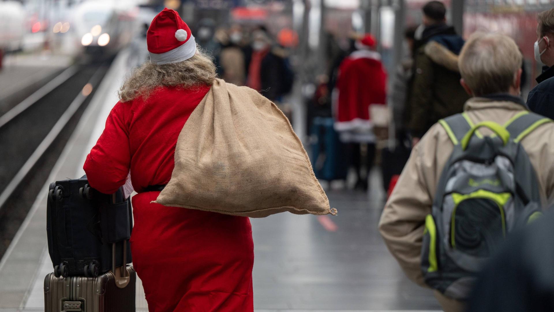 Ein Reisender im Weihnachtsmann-Kostüm geht mit einem Sack und Koffern am Hauptbahnhof zum Zug. | Sebastian Gollnow / WDR / dpa
