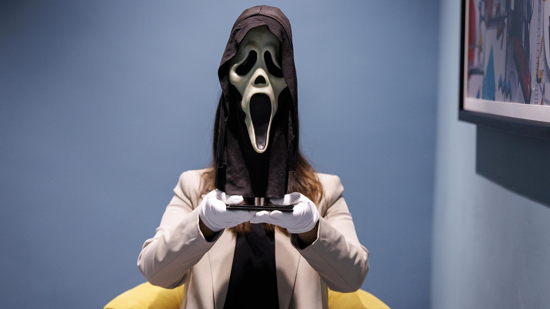 Eine Galeriemitarbeiterin posiert mit einer Maske, die im Film 