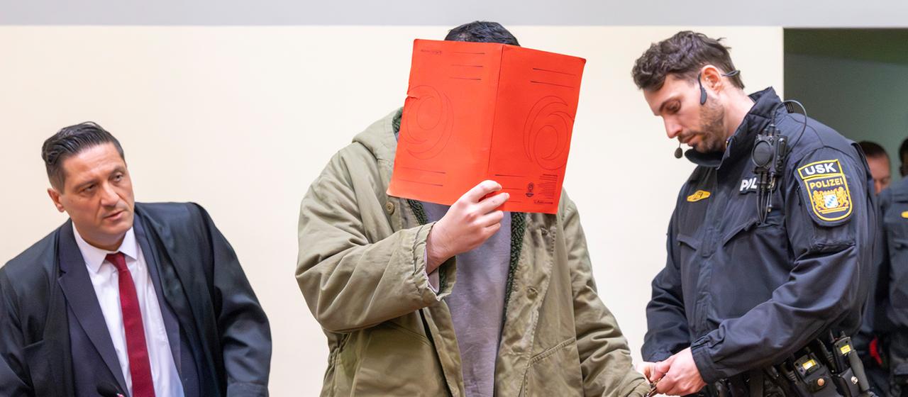 A defendant is led into a trial room.