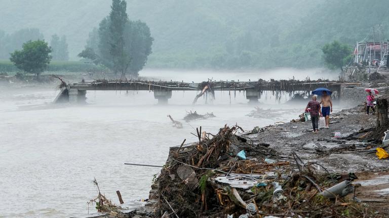 Menschen gehen an einer beschädigten Brücke im Huairou-Bezirk in Peking vorbei, nachdem schwere Regenfälle das Gebiet überflutet hatten.