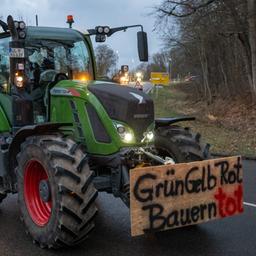 Nach einer Kundgebung des Bauernverbandes gegen die Sparpläne der Bundesregierung fahren Landwirte im Konvoi durch die Stadt Günzburg, auf einem Plakat steht "GrünGelbRot Bauern tot". 