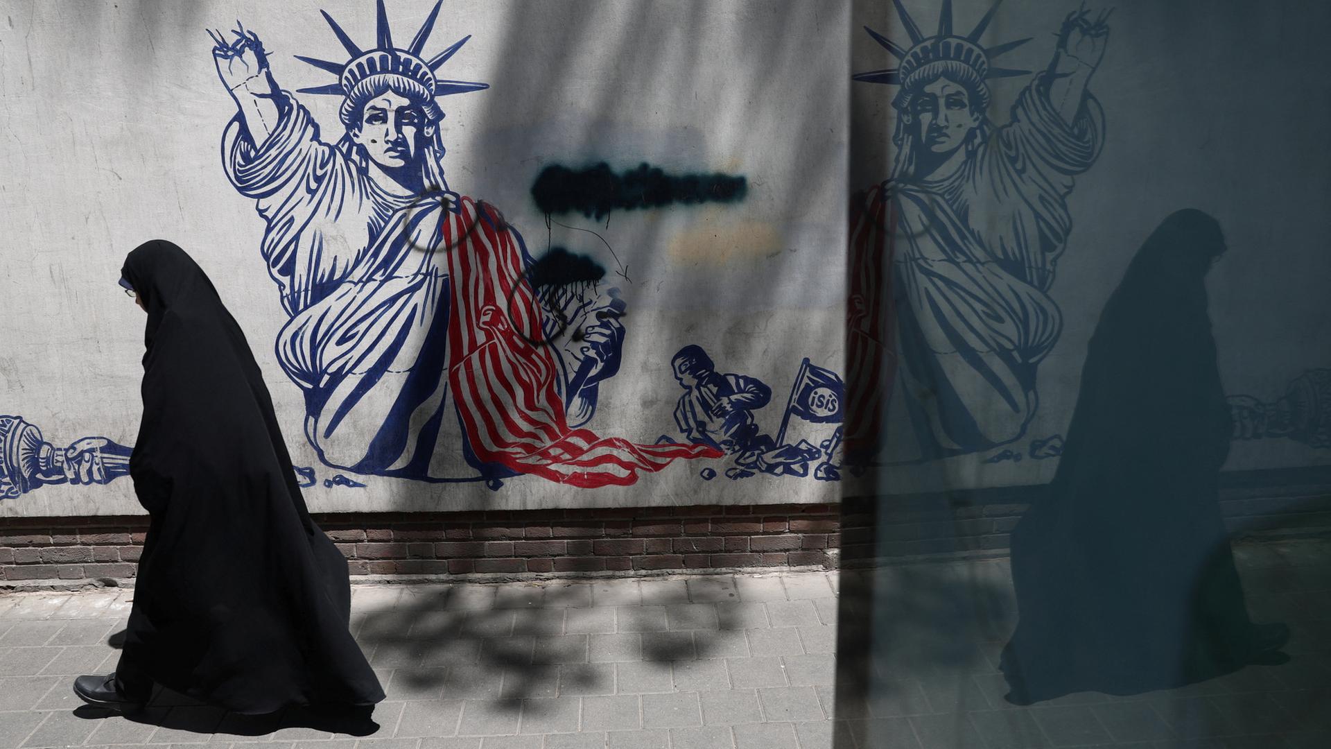 Eine verschleierte Frau l�uft an einer Wand mit einem Anti-US-Graffiti vorbei | via REUTERS
