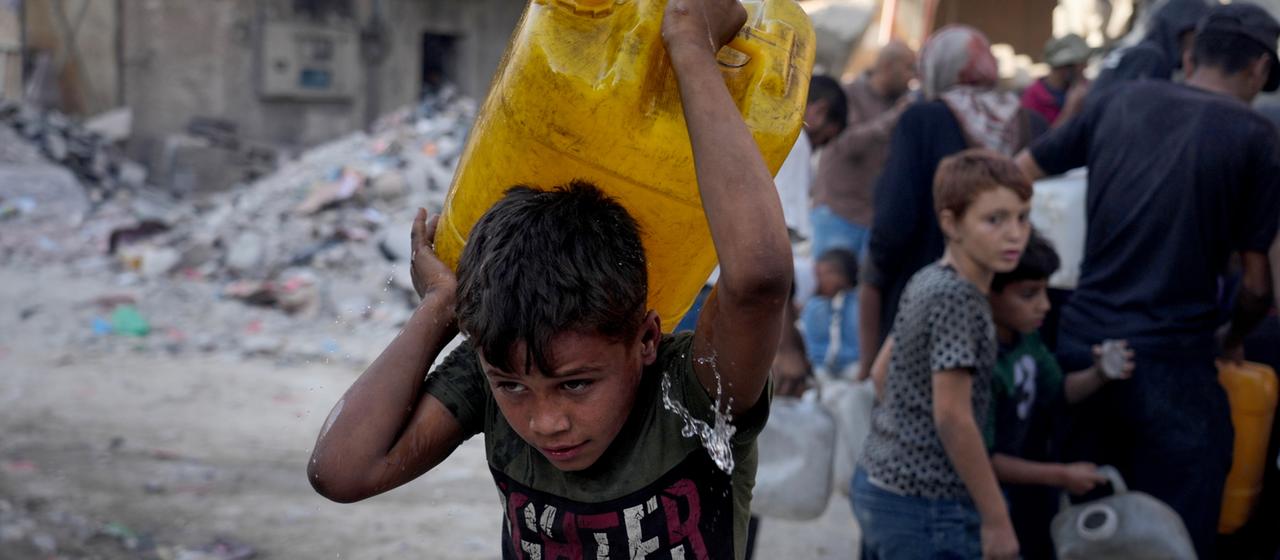 Ein palästinensisches Kind in Gaza-Stadt trägt einen Kanister mit Wasser.