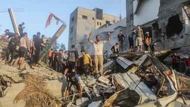 Palästinenser stehen auf den Trümmern eines eingestürzten Gebäudes in Chan Junis und suchen israelischen Angriffen nach Überlebenden und Opfern. 