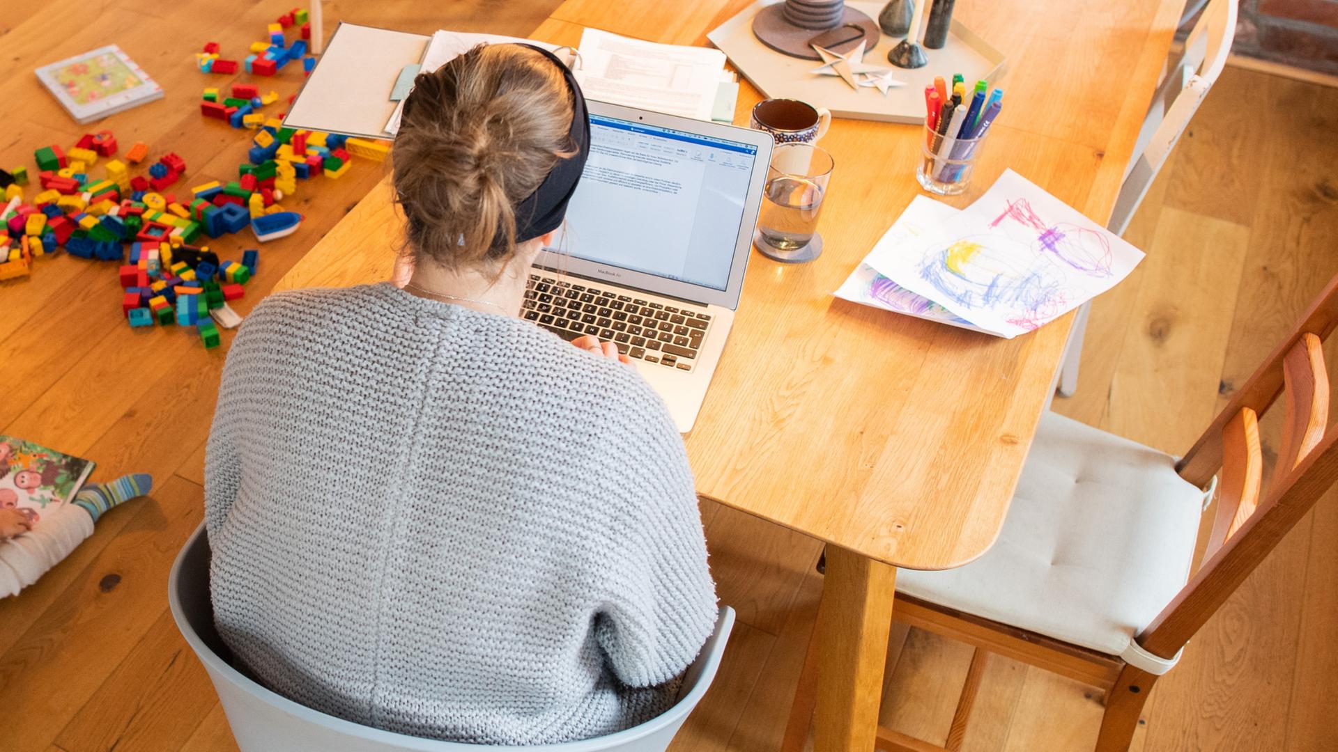 Eine Frau sitzt mit Laptop am KÃ¼chentisch. | dpa