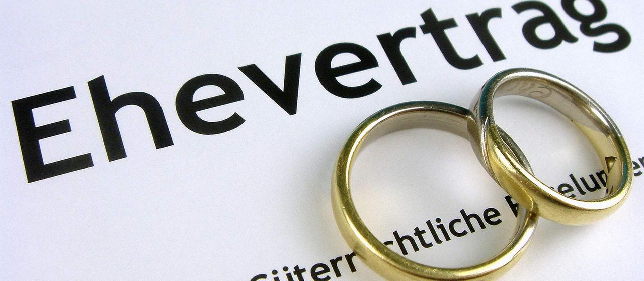 Ringe liegen auf einem Ehevertrag.