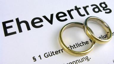 Ringe liegen auf einem Ehevertrag.