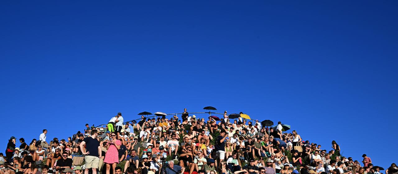 Menschen beobachten vom Olympiaberg in München die Sonnenfinsternis