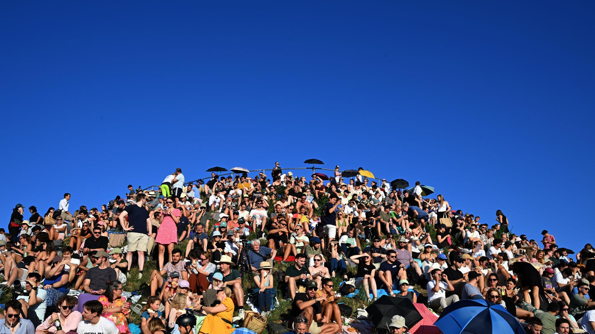 Menschen beobachten vom Olympiaberg in München die Sonnenfinsternis | Felix Hörhager/dpa