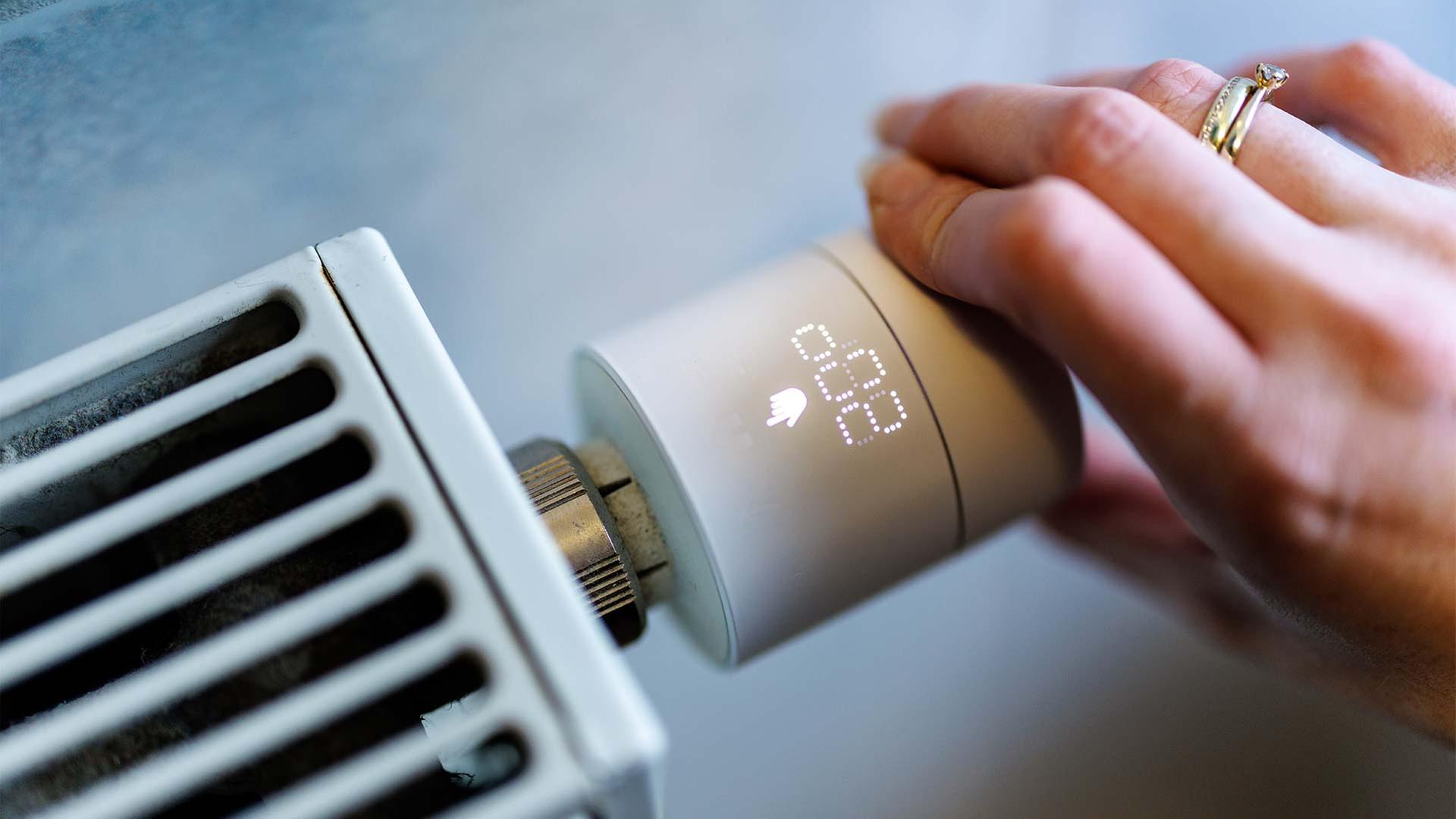 Eine Hand stellt an einem smarten Thermostaten die Temperatur ein. | picture alliance / dpa