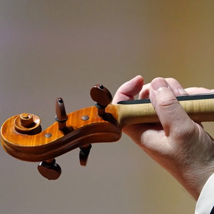 Hand eines Musikers eines Symphonieorchesters hält eine Geige