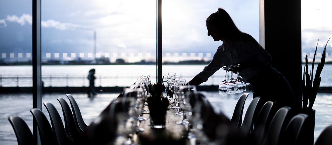 Eine Kellnerin deckt Tische in einem Hotel.