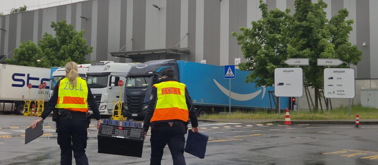 Zollbeamte gehen auf das Gelände eines Logistikunternehmens. 