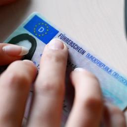 Eine Frau legt ihren Führerschein auf einen Tisch.