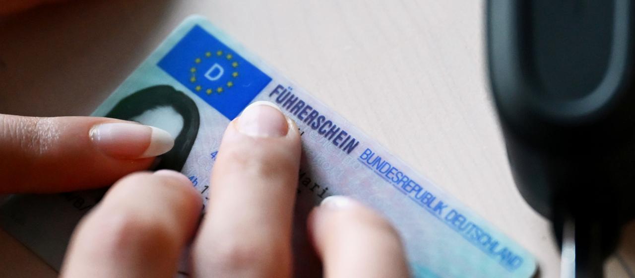 Eine Frau legt ihren Führerschein auf einen Tisch.