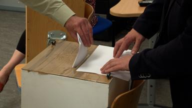 Ein Wähler gibt seinen Stimmzettel ab und steckt ihn in die Wahlurne.