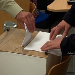 Ein Wähler gibt seinen Stimmzettel ab und steckt ihn in die Wahlurne.