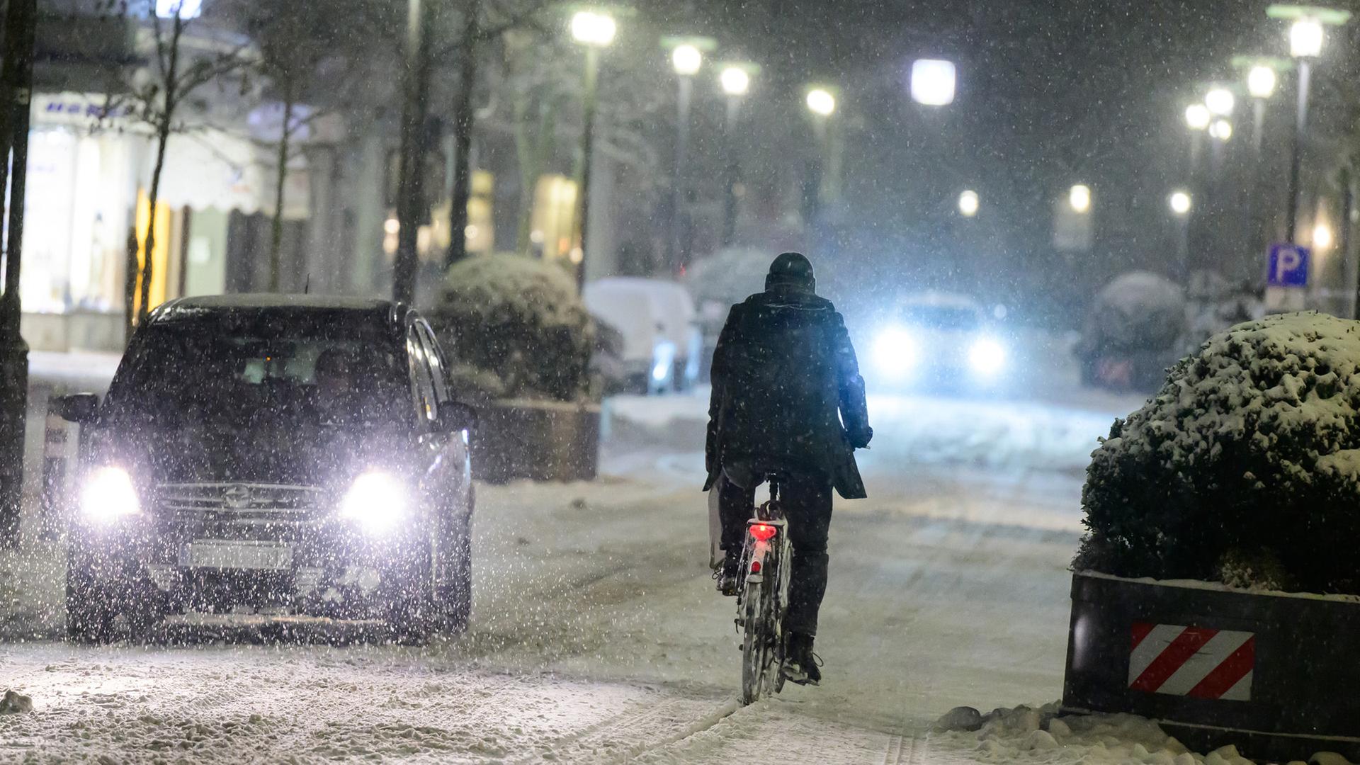 Ein Radfahrer fährt bei Schneefall neben Autos durch die Uelzener Innenstadt. | dpa