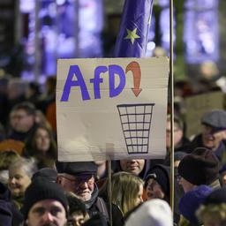 Auf einer Demo in Schwerin hält ein Teilnehmer ein Schild hoch: Darauf der Schriftzug AfD, der in einem Mülleimer landet.