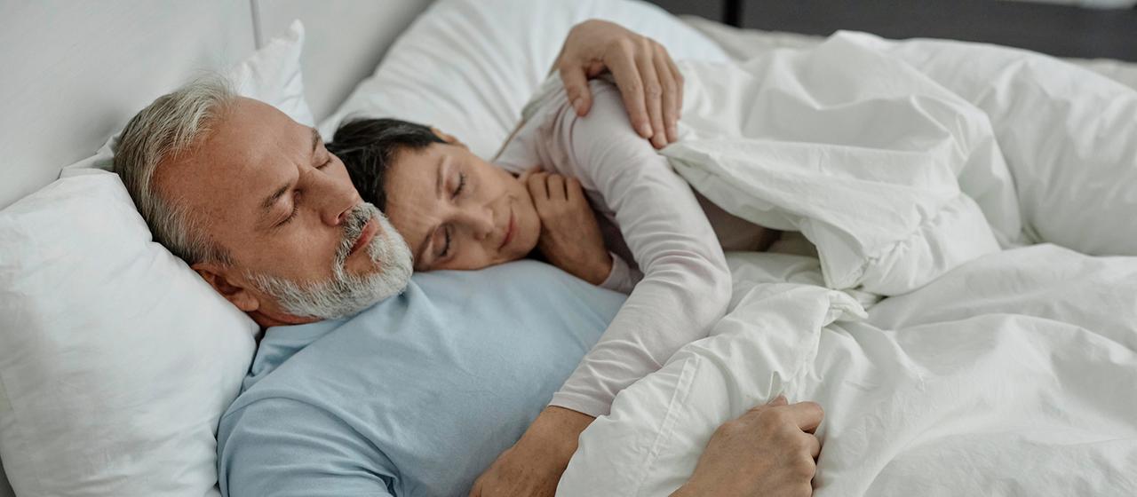 Ein Paar kuschelt im Bett beim Schlafen.