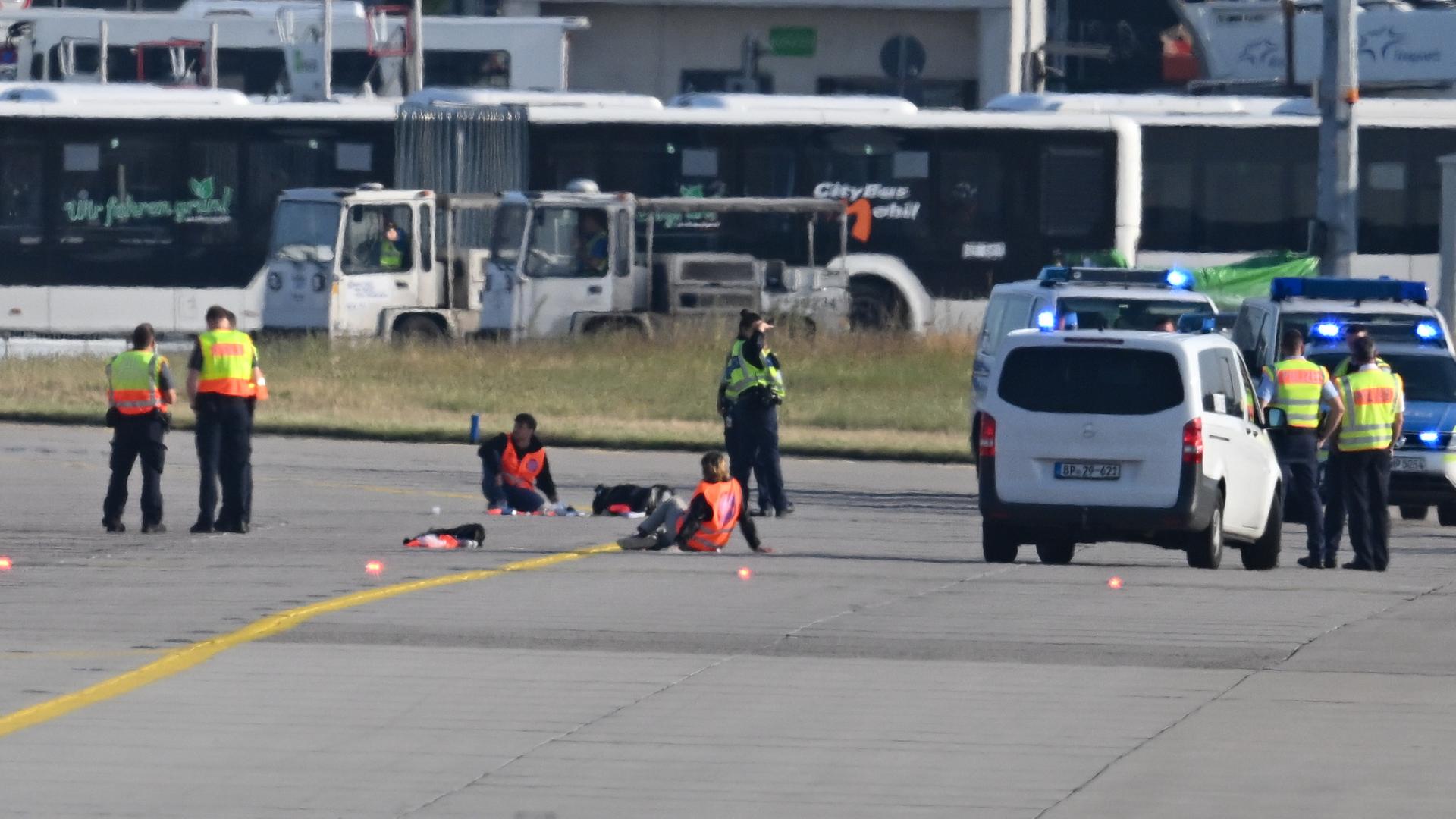 Einsatzkräfte stehen am Frankfurter Flughafen, wo sich zwei Aktivisten festgeklebt haben.  | picture-alliance/dpa