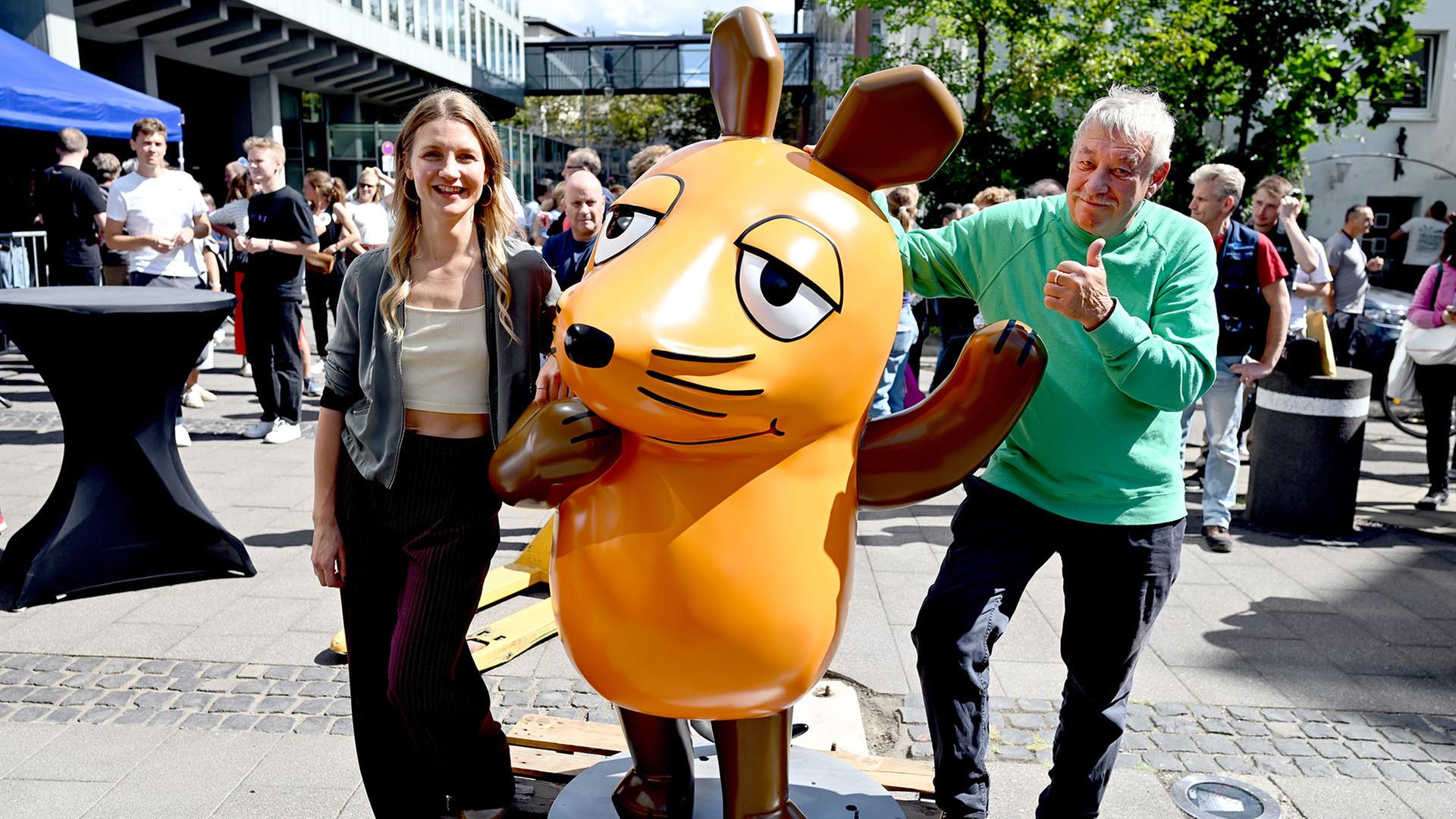 Christoph Biemann (r) und Jana Forkel stehen neben der reparierten Maus-Figur in KÃ¶ln. | dpa