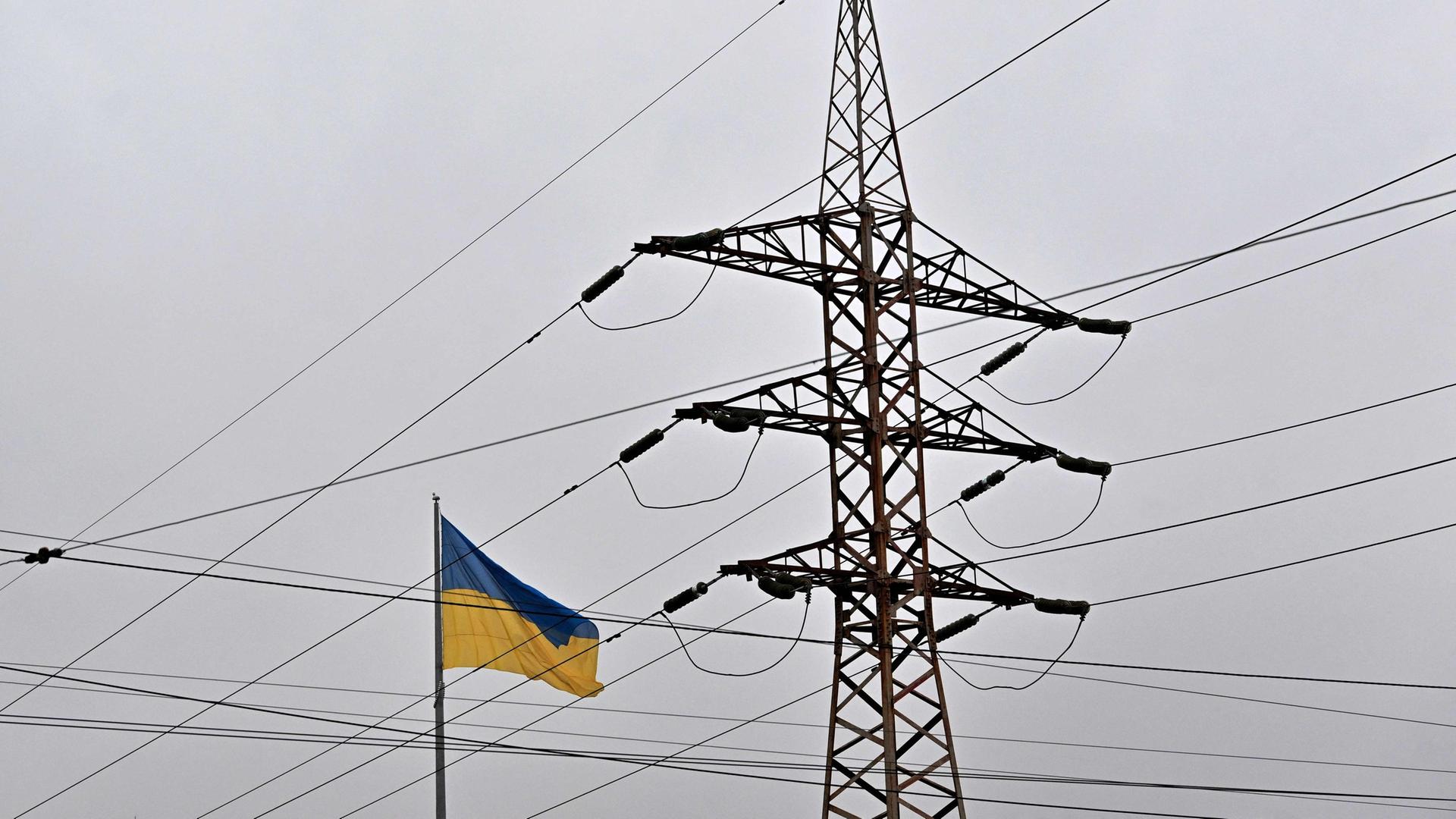 Eine ukrainische Flagge weht neben einem Strommast. | AFP