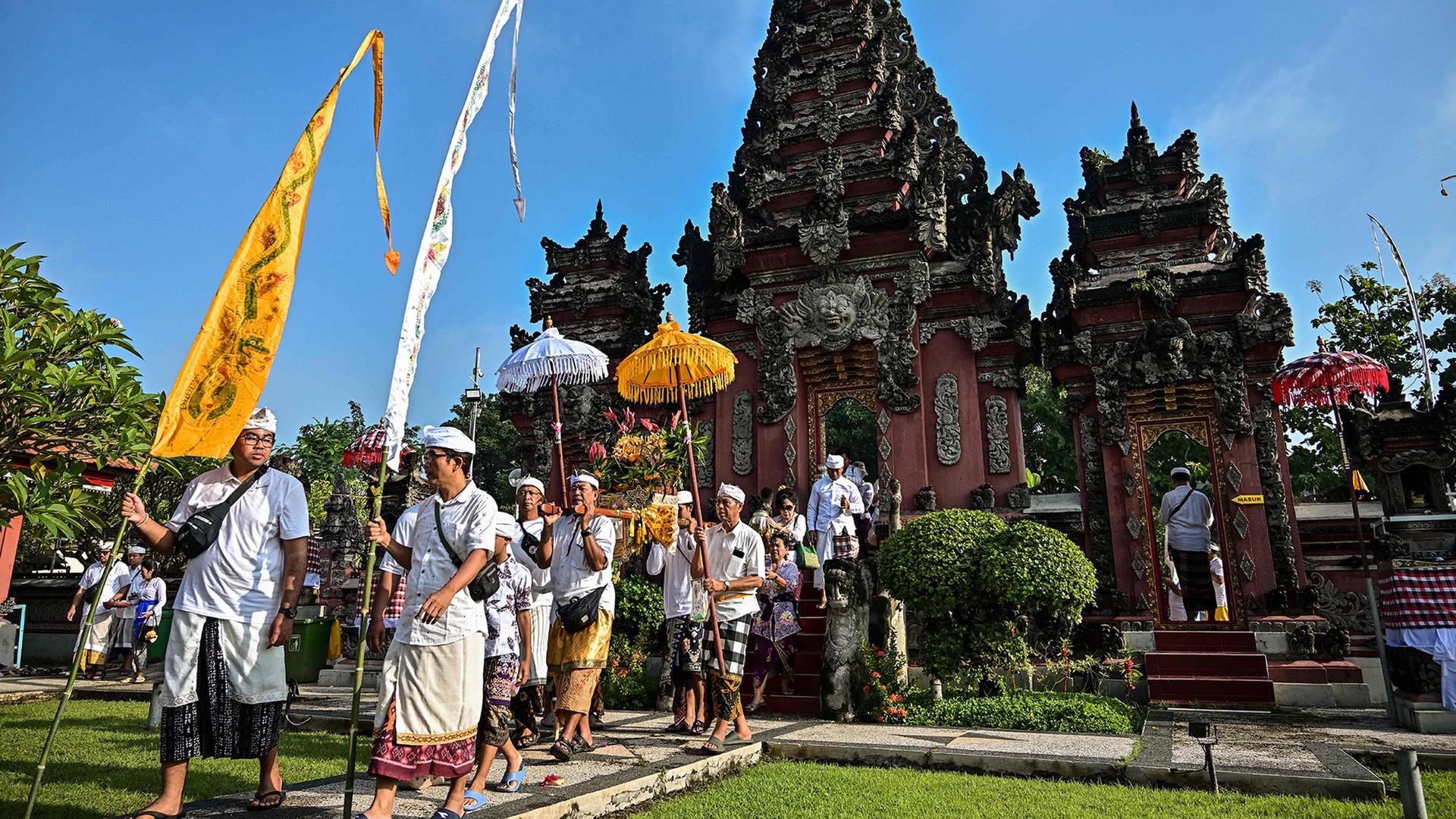 Hindus tragen Fahnen und Schirme bei einer Zeremonie vor einem Tempel. | AFP