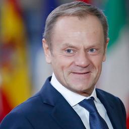 EU-Ratspräsident Donald Tusk lächelt vor Fahnen von EU-Staaten