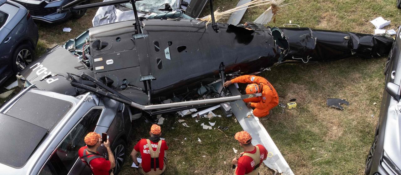 Rettungskräfte stehen bei einem auf Autos herabgestürzten Hubschrauber.