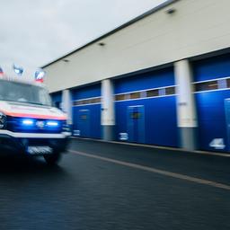 Ein Rettungswagen fährt mit eingeschaltetem Blaulicht über eine Straße. 