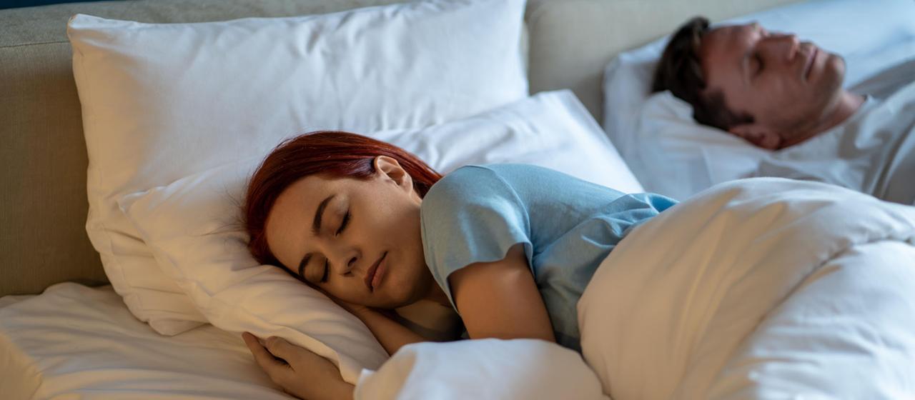 Eine Frau und ein Mann liegen schlafend in einem Bett.