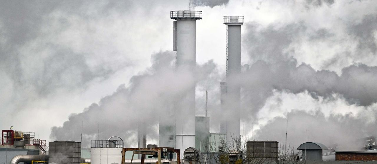 Rauchende Schornsteine einer Industrieanlage.