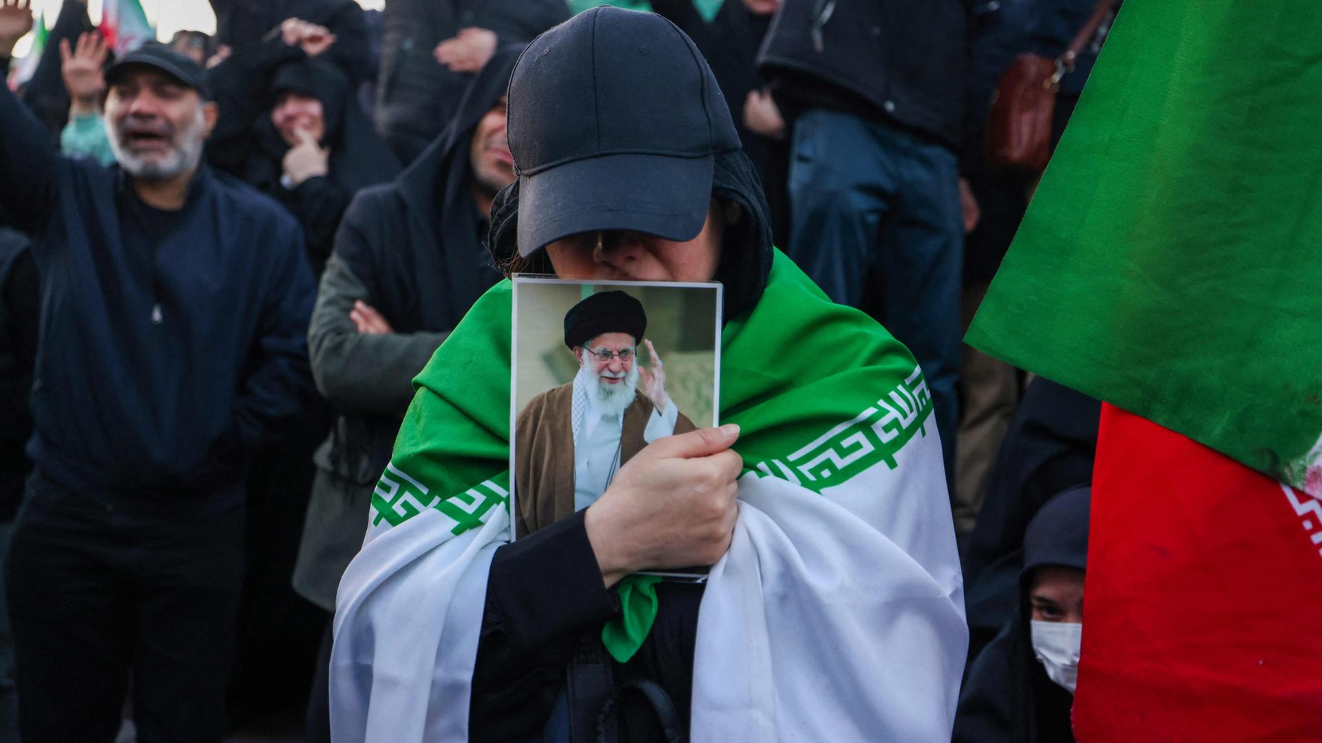 Eine Frau in Teheran (Iran) hält ein Foto von Ali Chamenei. | AFP