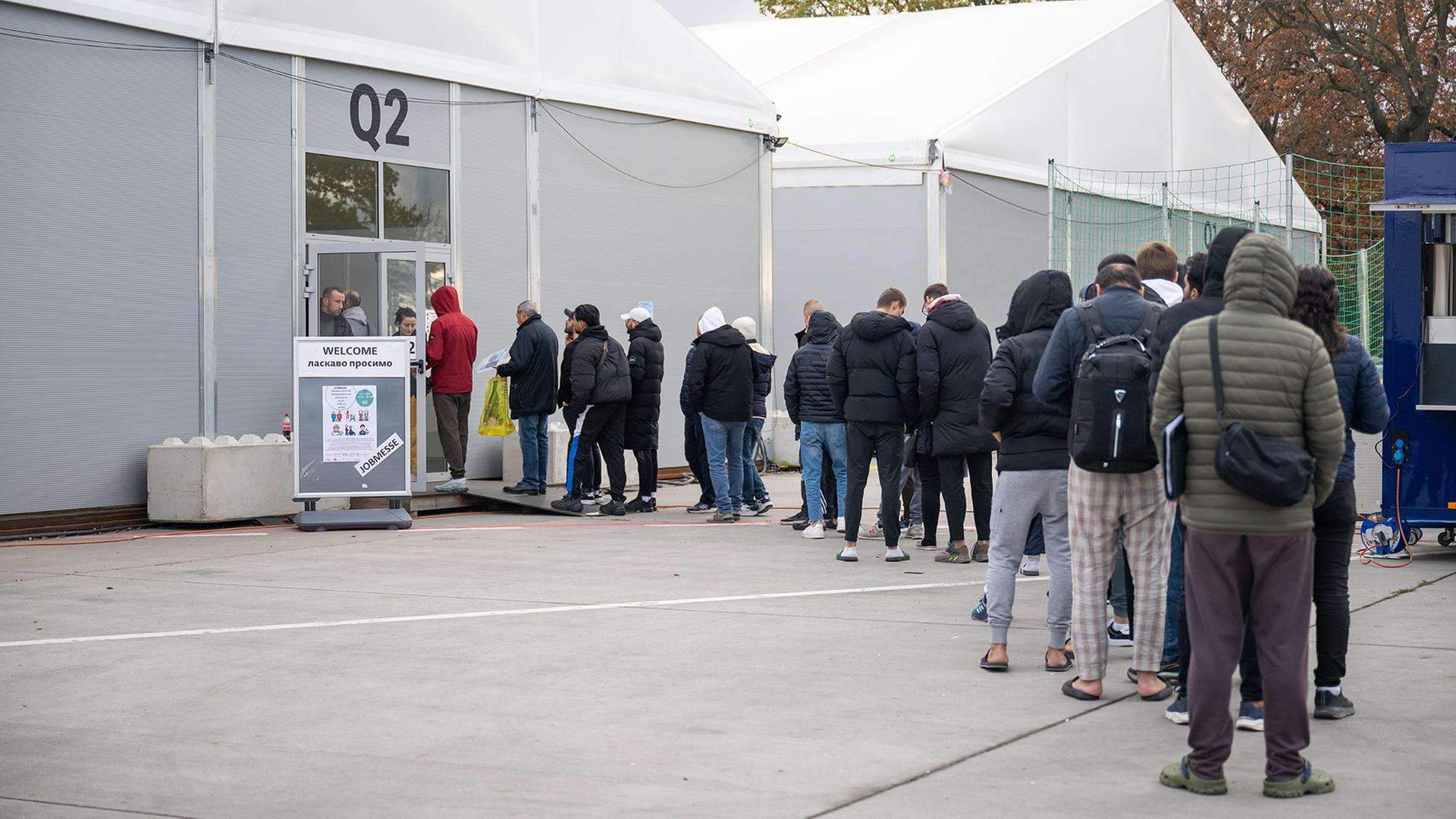 Geflüchtete stehen in einer Schlange vor einer Leichtbauhalle in Berlin-Tegel. | dpa