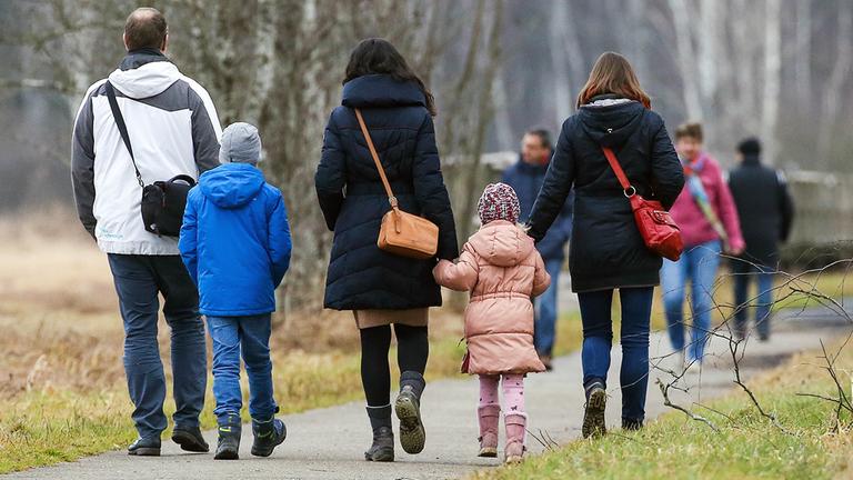 Spaziergänger mit Kindern sind auf einem Rundweg am Federsee unterwegs.