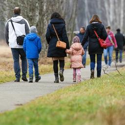 Spaziergänger mit Kindern sind auf einem Rundweg am Federsee unterwegs.
