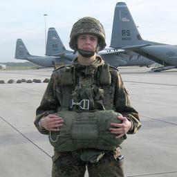 Annika Schröder steht in Uniform auf einem Rollfeld vor Flugzeugen.