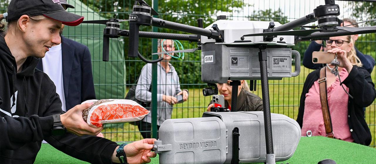 Eine Lieferdrohne wird in der Stadt Wusterhausen mit einem eingepackten Brot beladen | picture alliance/dpa Eine Lieferdrohne wird in der Stadt Wusterhausen mit einem eingepackten Brot beladen