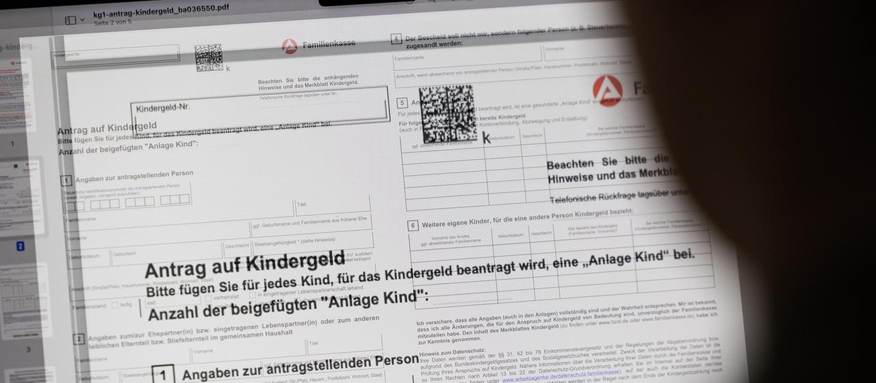 Ein Mensch sitzt vor einem Kindergeld-Antrag an einem Computer
