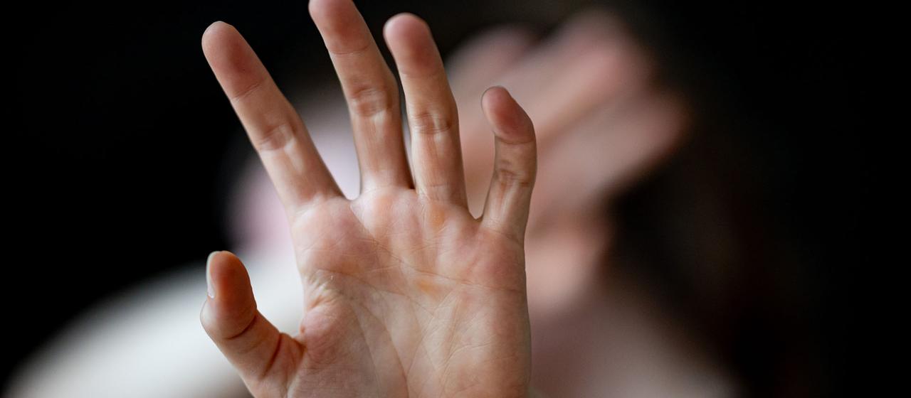 Eine Frau hält ihre Hände vor das Gesicht. 