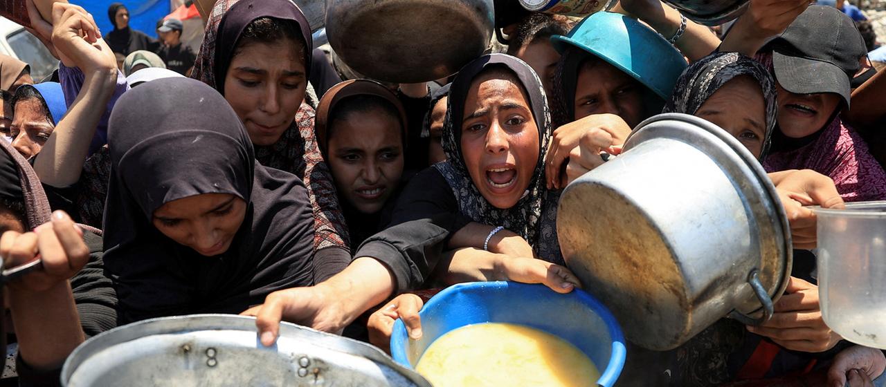 Palästinenser warten an einer Suppenküche in Gaza-Stadt auf Essen.