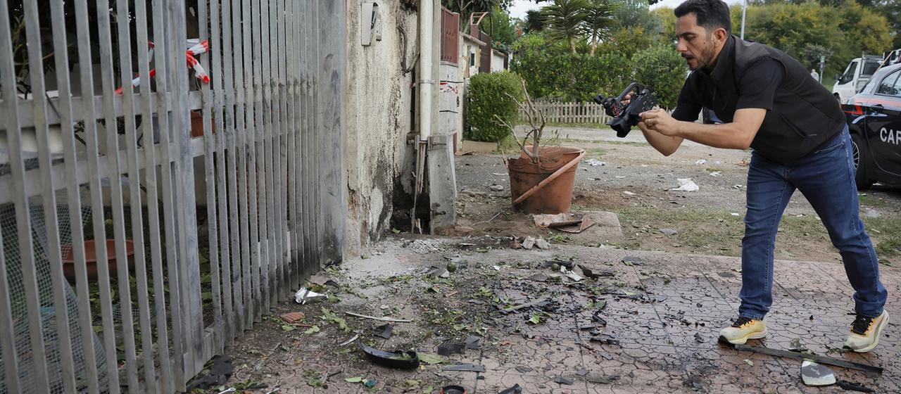 Ein Reporter filmt Teile eines Autos, die auf dem Boden liegen, nachdem unter dem Auto in Pome ein Sprengsatz detoniert ist.