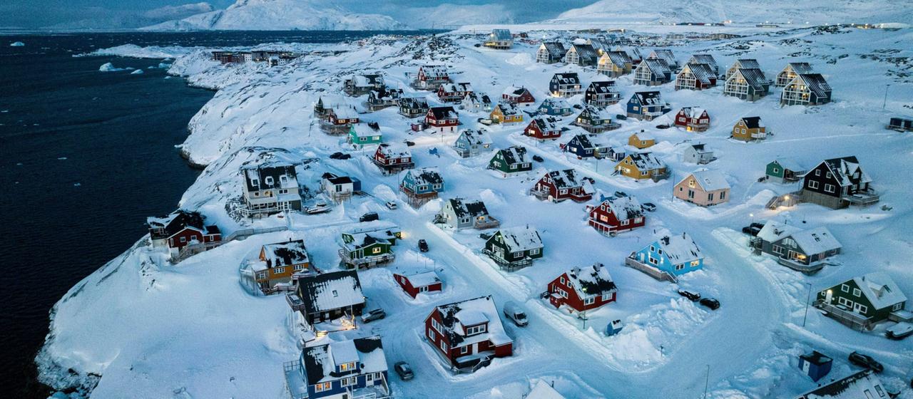 Eine Luftaufnahme von shcneebedeckten Häusern im Dämmerlicht in Nuuk auf Grönland.