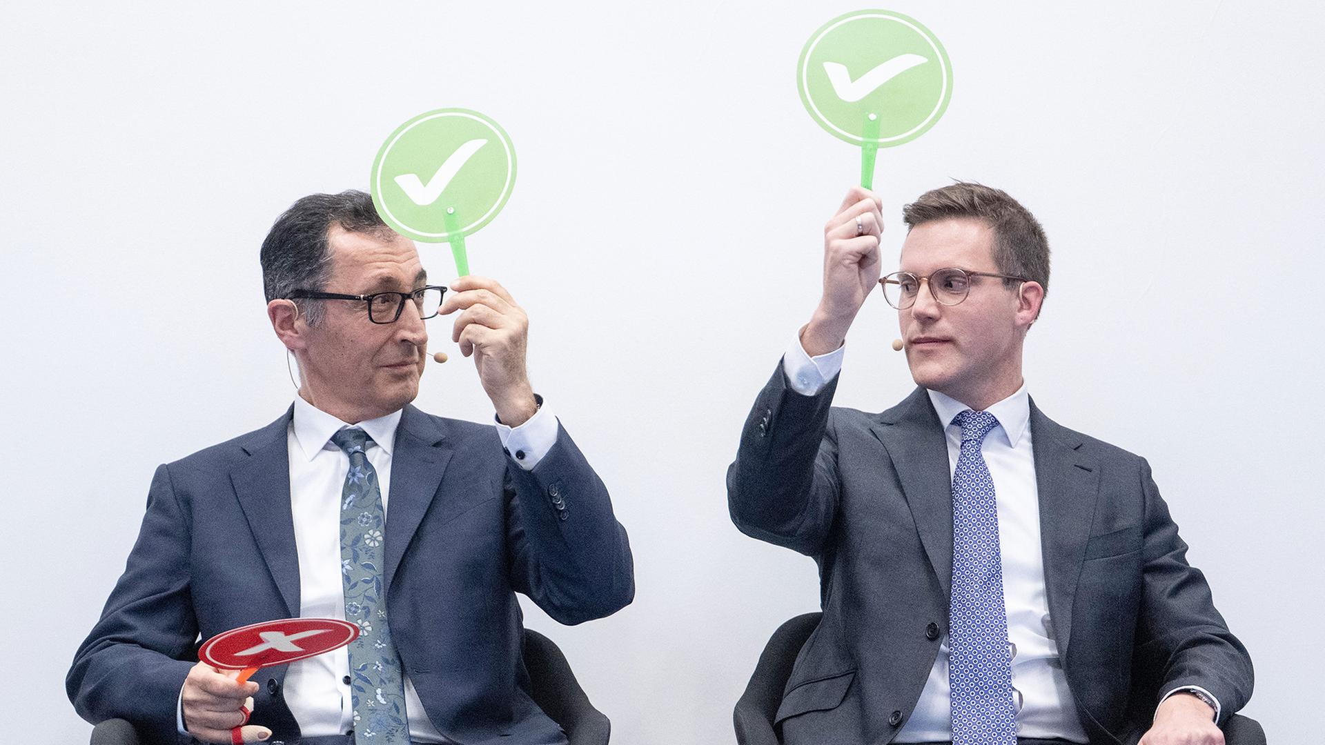 Cem �zdemir und Manuel Hagel halten gr�ne Schilder mit einem wei�en Haken darauf in der Hand. | Marijan Murat/dpa