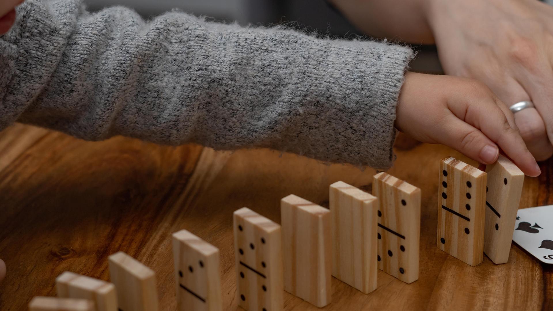 Ein Kind und eine erwachsene Person spielen Domino. | picture alliance / imageBROKER