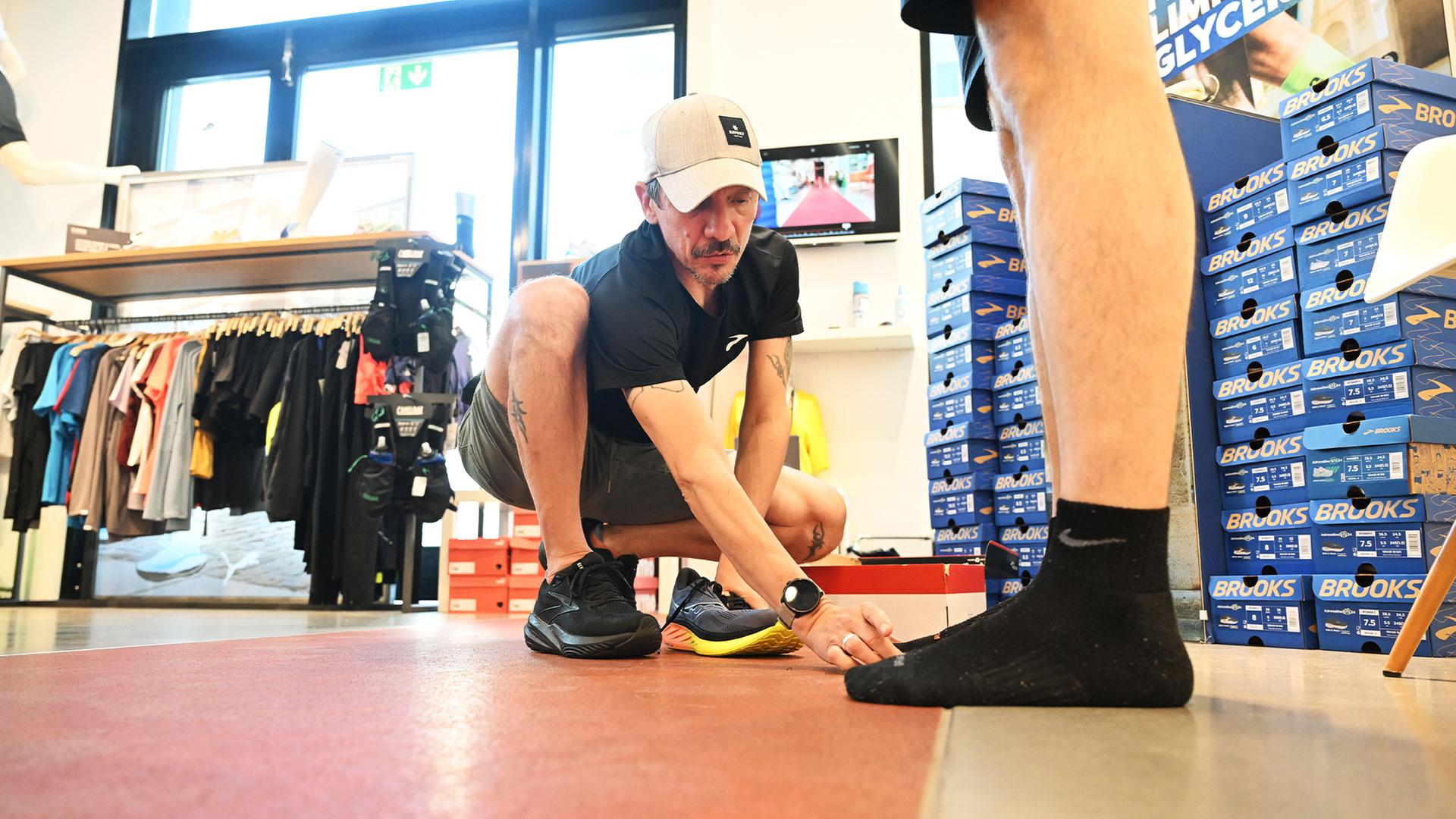 Petar Punjek, Filialleiter des Laufsportfachgeschäft Rennwerk, berät einen Kunden. | picture alliance/dpa